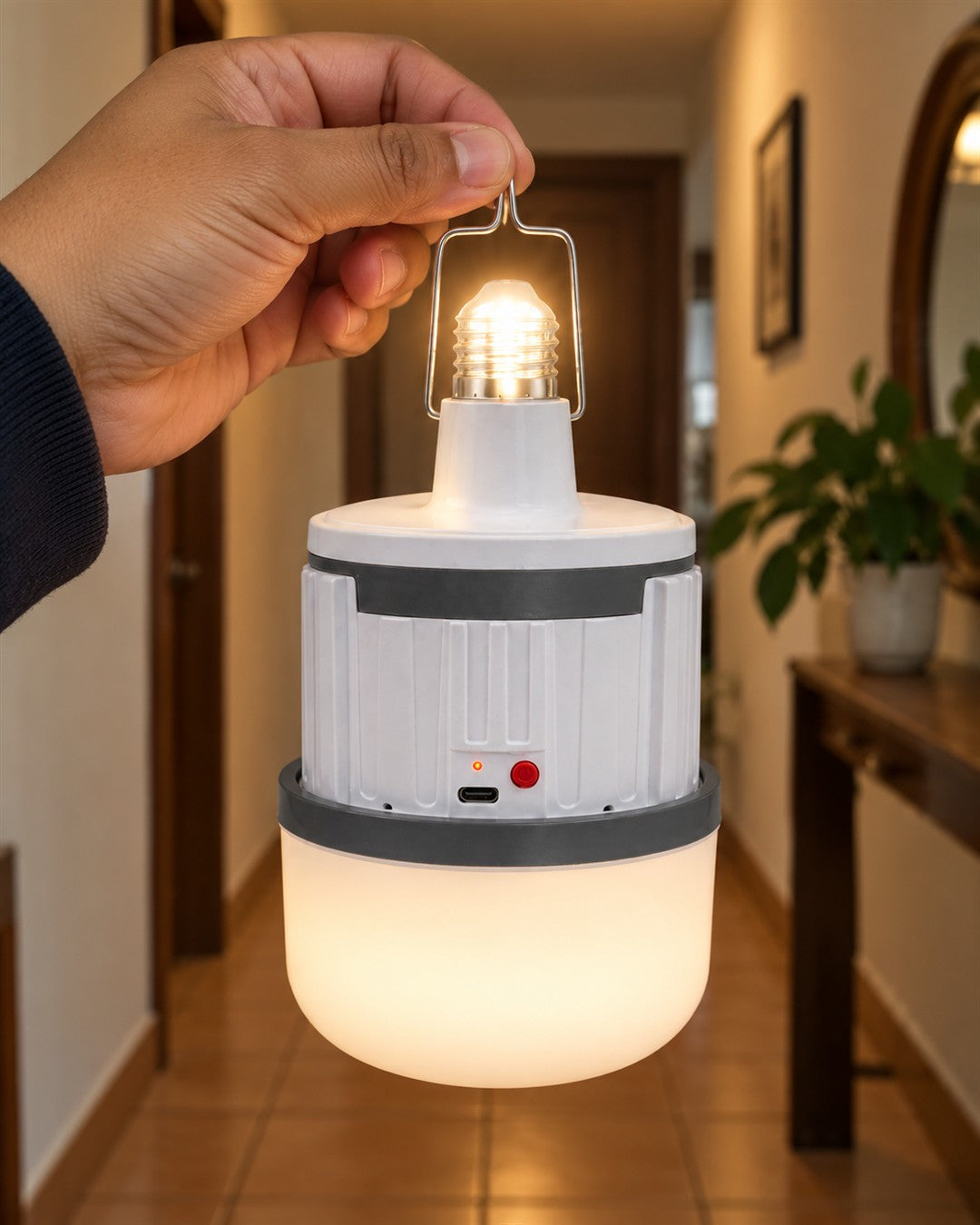Bombillo LED recargable tipo farol con gancho: cuerpo cilíndrico blanco acanalado con una banda gris oscura ancha en la parte superior en la mano