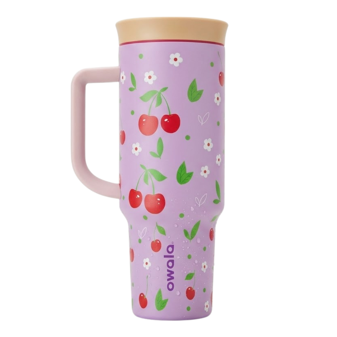 Vaso térmico Owala de 40 onzas en color lila o lavanda mate. El diseño presenta un patrón de cerezas rojas con hojas verdes, acompañadas de pequeñas flores blancas y puntos verdes. Incluye una tapa en color crema, asa ergonómica lila y el logotipo de Owala en color morado.