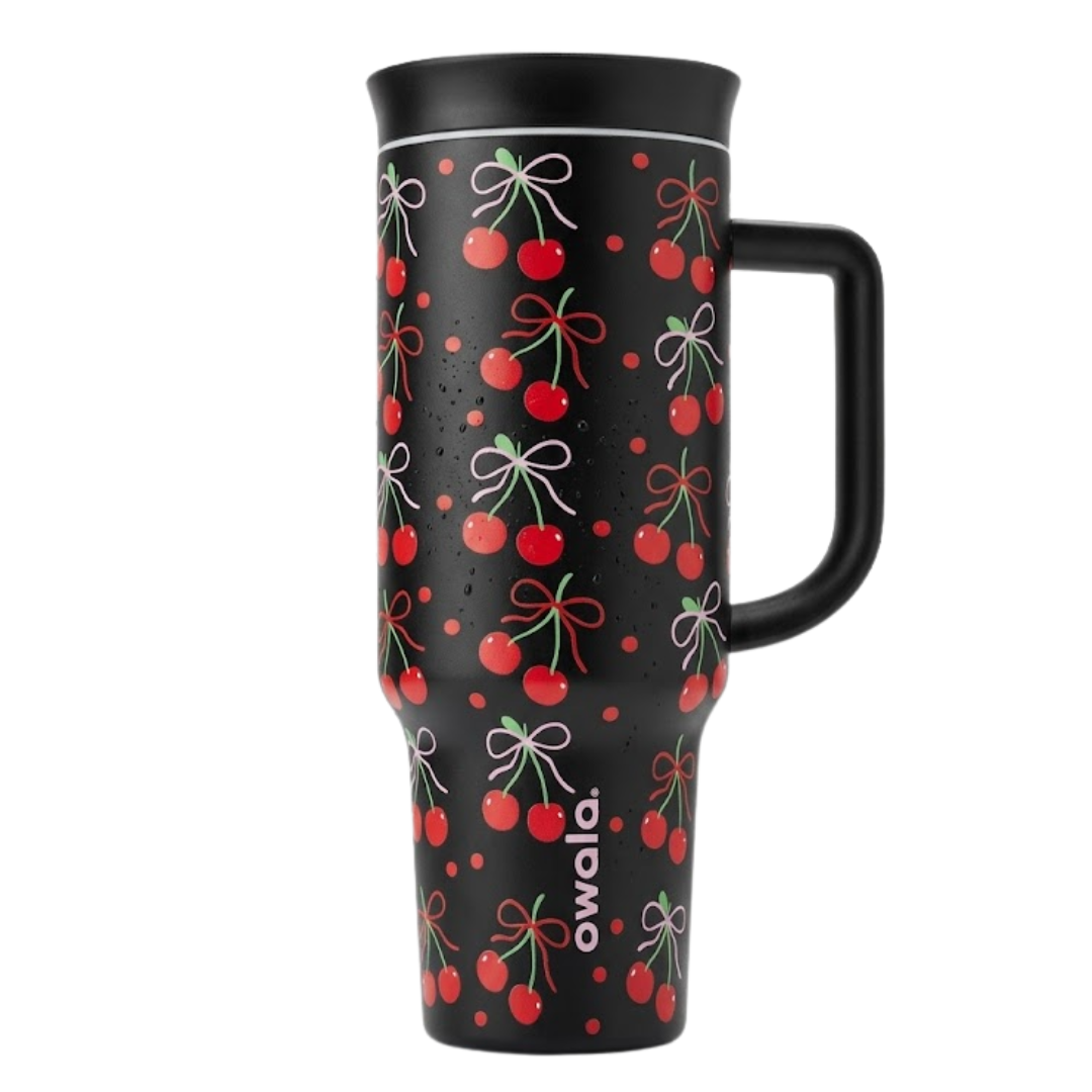 Vaso térmico Owala de 40 onzas en color negro mate con un patrón repetitivo de cerezas rojas con lazos rosas y rojos. El vaso incluye un asa ergonómica negra. El logotipo de Owala aparece en vertical en la parte inferior.