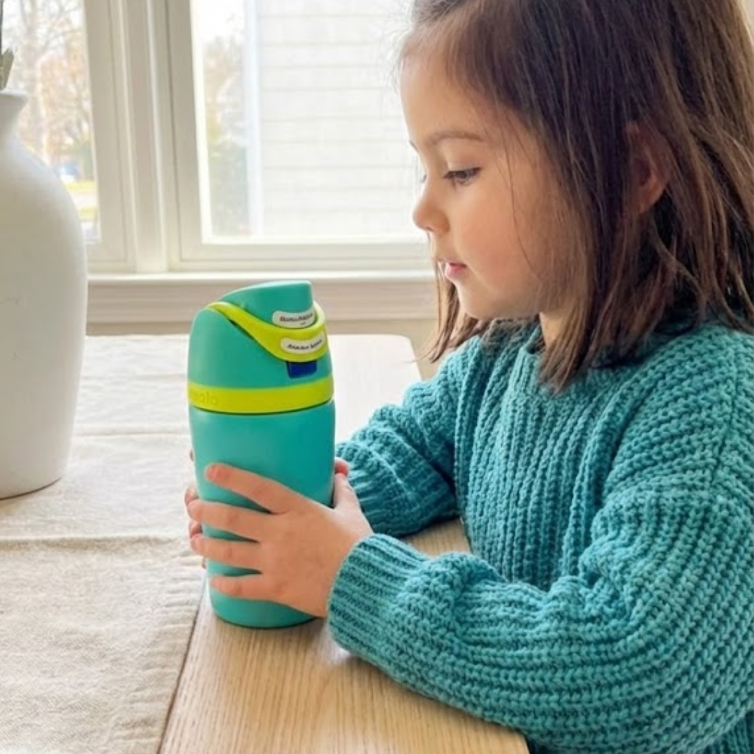 otella térmica infantil Owala FreeSip de 12 onzas. El cuerpo del termo es color aqua mate, la tapa combina bloques de color turquesa y verde lima brillante, y un botón de apertura.
