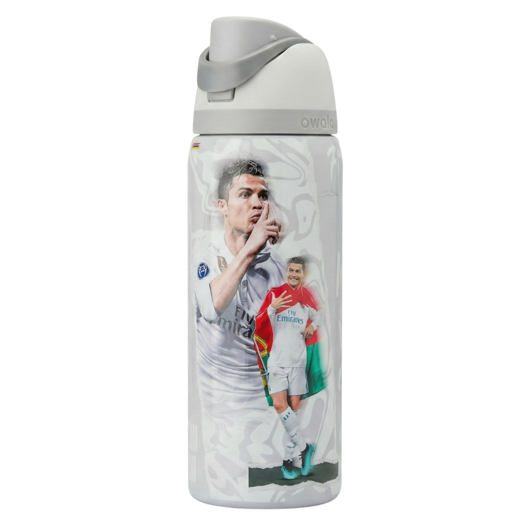 Botella térmica Owala FreeSip de 32 onzas en color blanco con diseño conmemorativo de Cristiano Ronaldo en el Real Madrid. Se ve al jugador haciendo su icónico gesto de silencio y otra imagen celebrando con la bandera de Portugal sobre los hombros vistiendo la equipación blanca de "Fly Emirates". La tapa es blanca con el asa de seguridad en color gris claro.