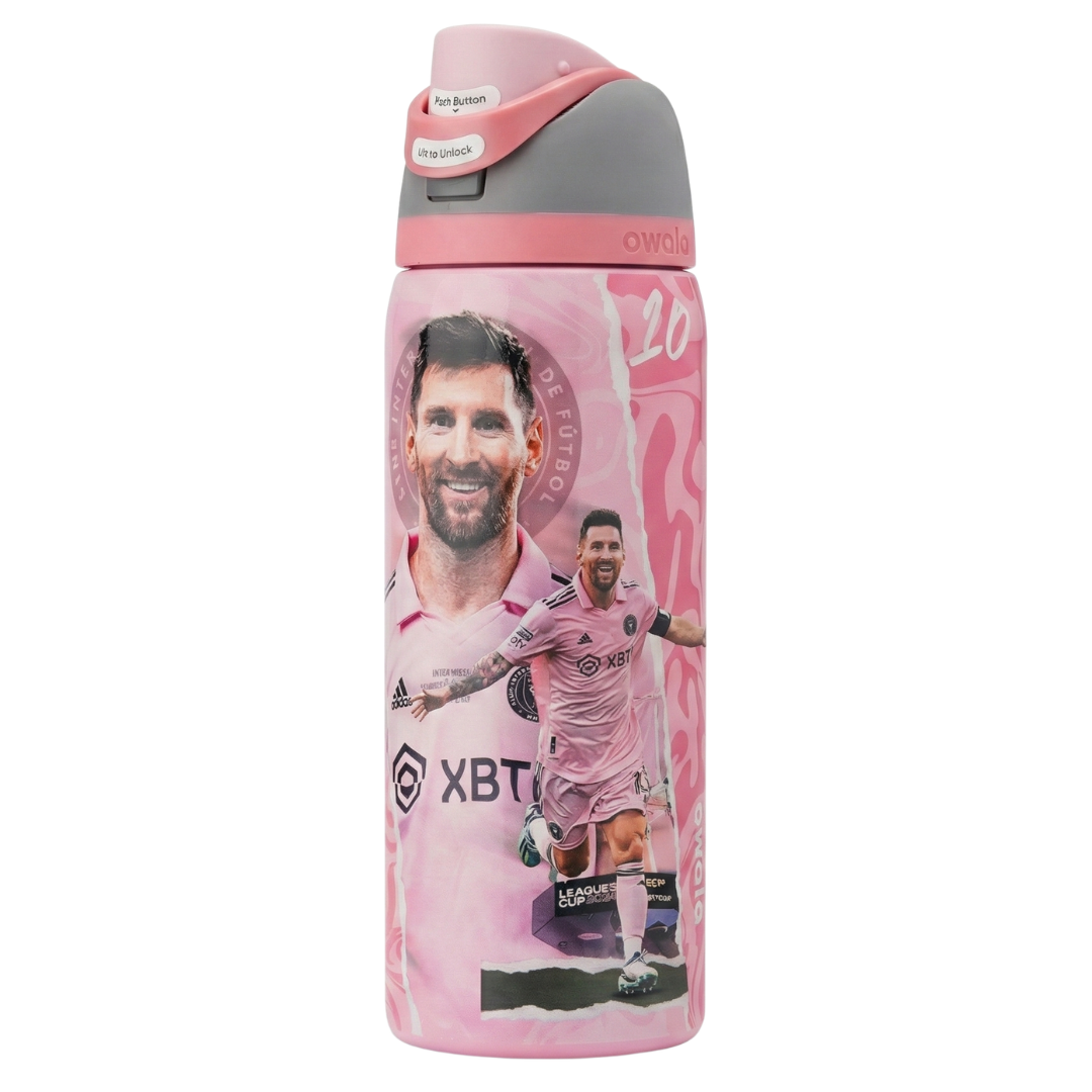 Botella térmica Owala FreeSip de 32 onzas en color rosa pastel con diseño conmemorativo de Lionel Messi en el Inter Miami. Presenta al jugador sonriendo con la camiseta rosa oficial y otra imagen de él celebrando un gol. La tapa combina tonos de rosa claro, gris y un botón blanco. Incluye boquilla doble FreeSip y asa de transporte.