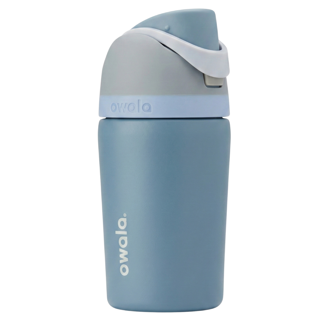 Botella térmica de 12 onzas para niños modelo Owala Kids FreeSip en color azul denim mate. La tapa de seguridad incluye un asa de transporte gris claro, detalles en azul pálido y un botón de apertura gris. Cuerpo de acero inoxidable con el logotipo de Owala.