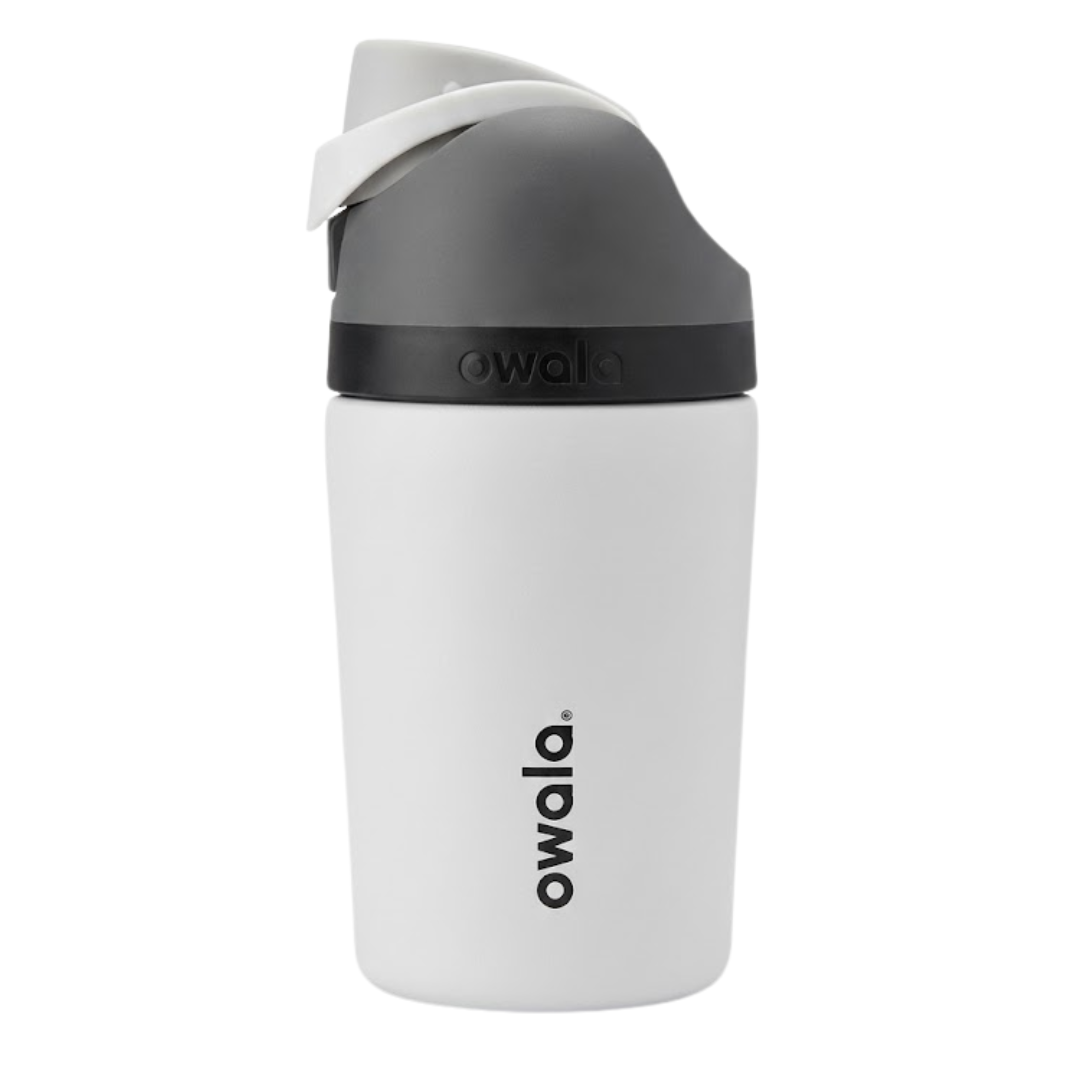 Botella térmica de 12 onzas para niños modelo Owala Kids FreeSip en color blanco hueso mate (Shale Pale). La tapa incluye un asa de transporte en blanco, un botón de apertura gris oscuro y detalles en gris. Cuerpo de acero inoxidable con logotipo de Owala en gris.
