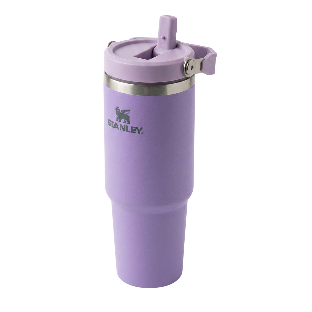 Termo de acero inoxidable de 30 onzas modelo Stanley IceFlow Flip Straw. El cuerpo es de color lila o lavanda con acabado mate. La tapa de color lila incluye una pajilla abatible integrada (flip straw) y un asa de transporte giratoria del mismo tono, con el icono del oso alado de Stanley grabado en el costado de la tapa.