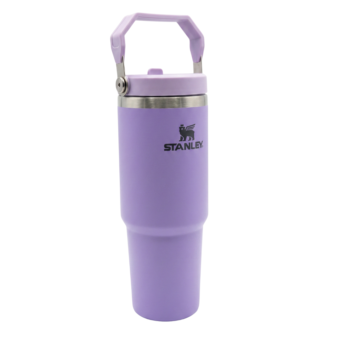 Termo de acero inoxidable de 30 onzas modelo Stanley IceFlow Flip Straw. El cuerpo es de color lila o lavanda con acabado mate. La tapa de color lila incluye una pajilla abatible integrada (flip straw) y un asa de transporte giratoria del mismo tono, con el icono del oso alado de Stanley grabado en el costado de la tapa.
