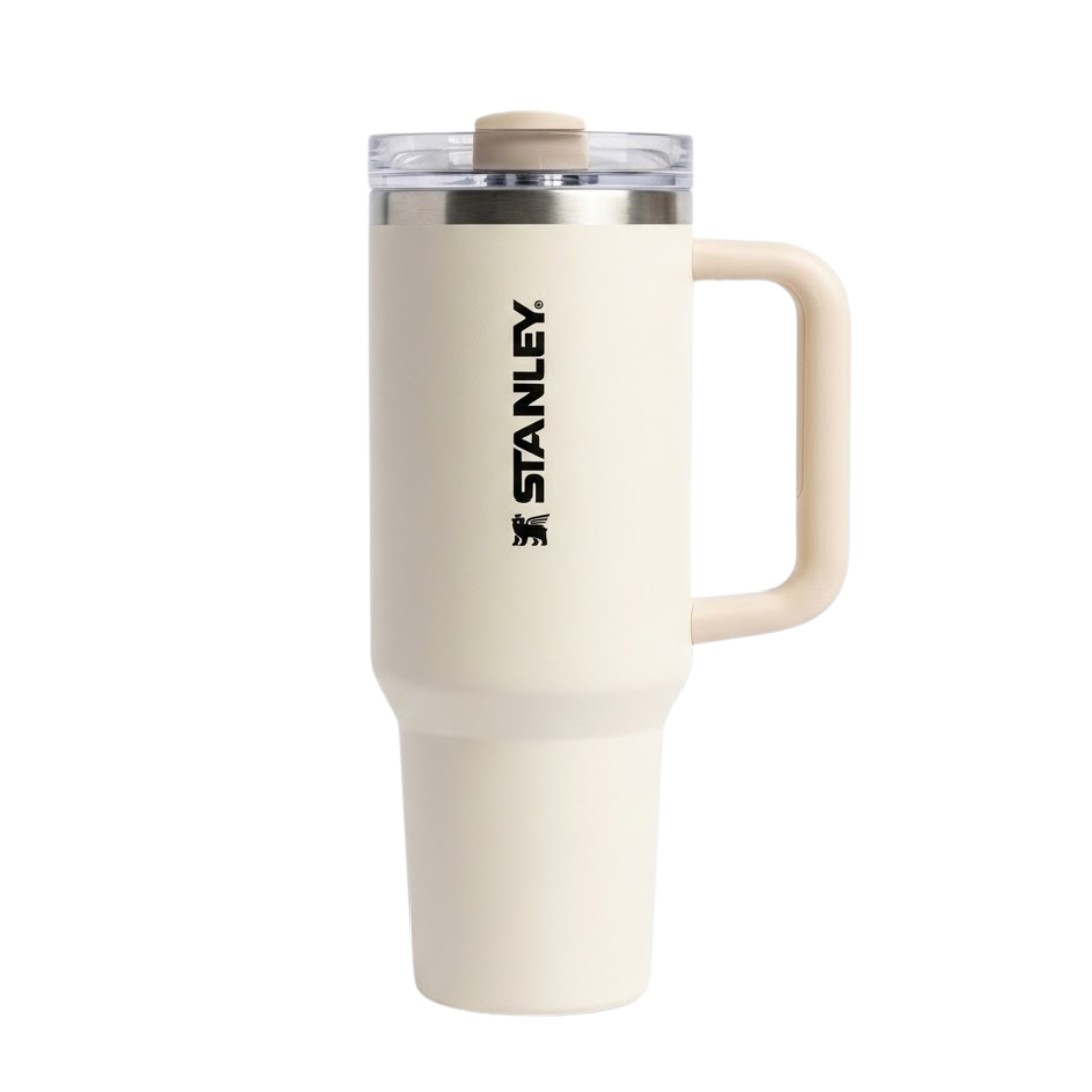 Vaso térmico de 40 onzas Stanley Quencher H2.0 en color crema o beige arena (Birch). La tapa FlowState™ presenta detalles en un tono beige ligeramente más oscuro que el cuerpo. El asa de transporte es robusta en el mismo color crema con refuerzo interno. El logotipo de Stanley destaca en color negro vertical, otorgando un aspecto minimalista y limpio.