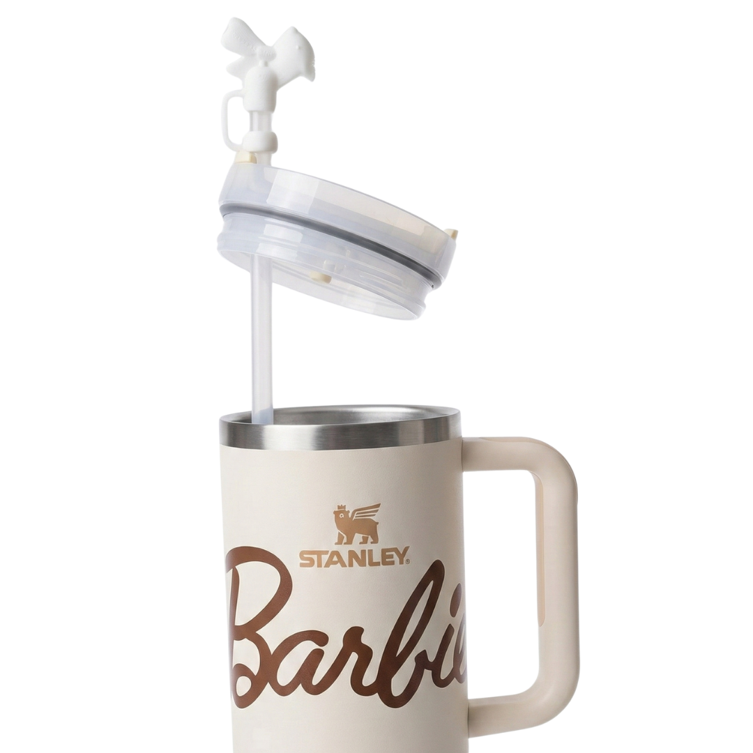 Vaso térmico Stanley x Barbie de 40 onzas en color beige crema (Birch) con acabado mate. Presenta un estampado sutil de estrellas y la silueta icónica de Barbie en tonos arena. El logotipo de Stanley y el nombre de Barbie resaltan en color marrón chocolate. Incluye la tapa FlowState™ con detalles en beige y el sello del 65 aniversario en la base.